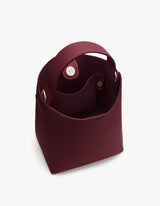 Open handbag with round handles and button closure on top.