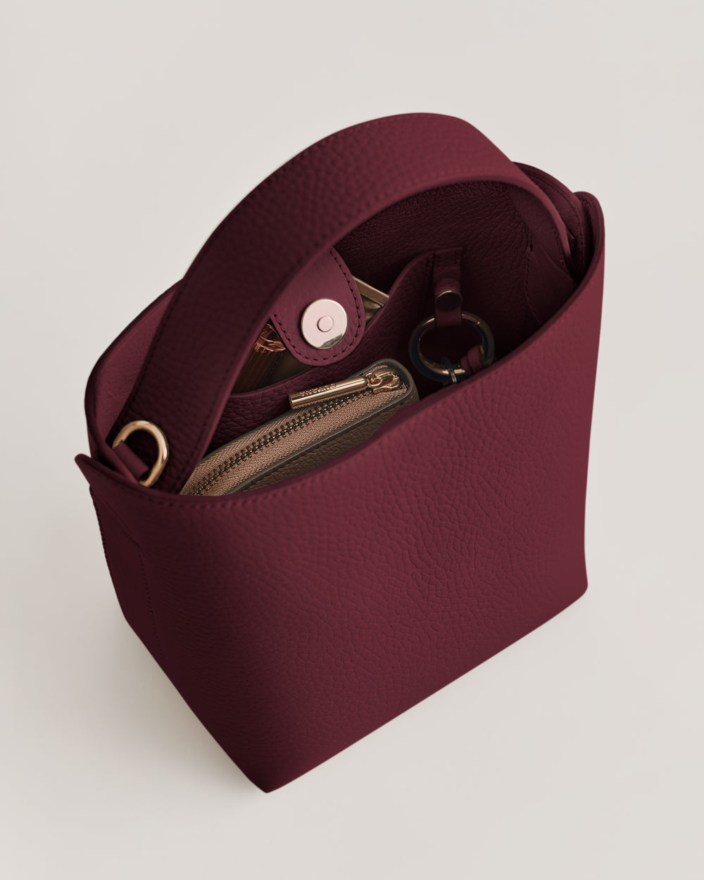 Handbag with an open top, showing a zippered pouch and a keyring inside.
