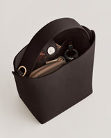 Bucket bag with metal clasp, containing a zippered pouch and keyring inside.