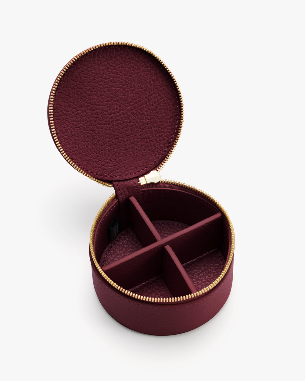Round jewelry case with open zipper and divided compartments inside.