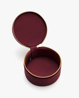 Round jewelry case with a zipper, open to reveal interior space.
