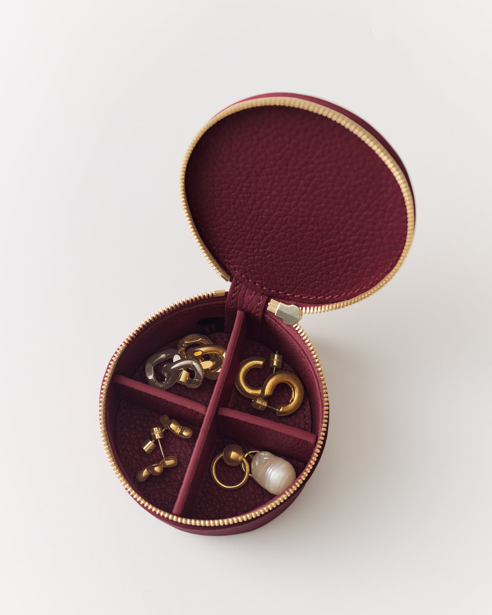 Round jewelry case with sections containing various earrings and a ring.