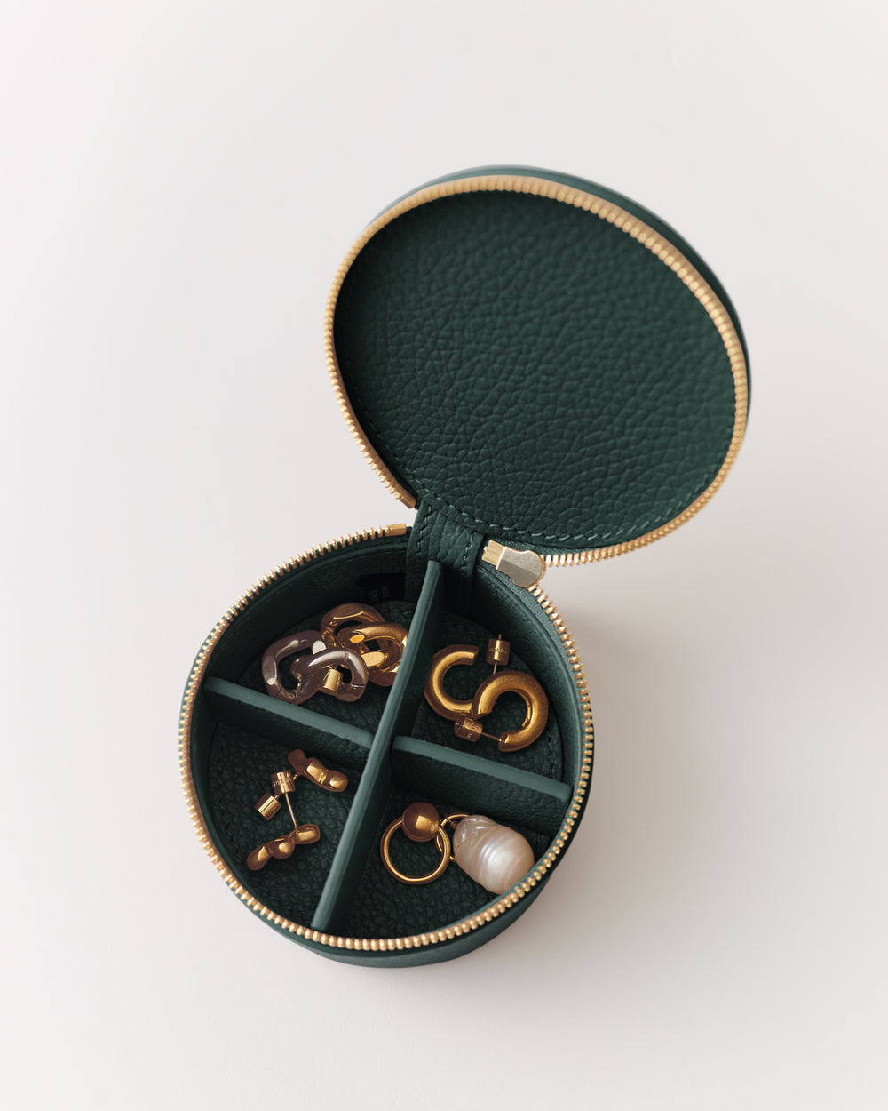 Round jewelry case with various earrings inside.