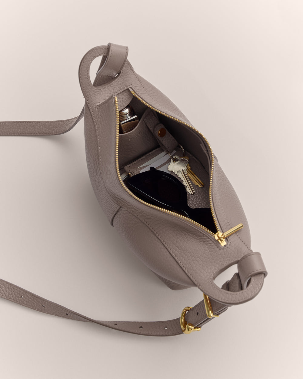 Open handbag with keys, folded sunglasses, and bottles inside