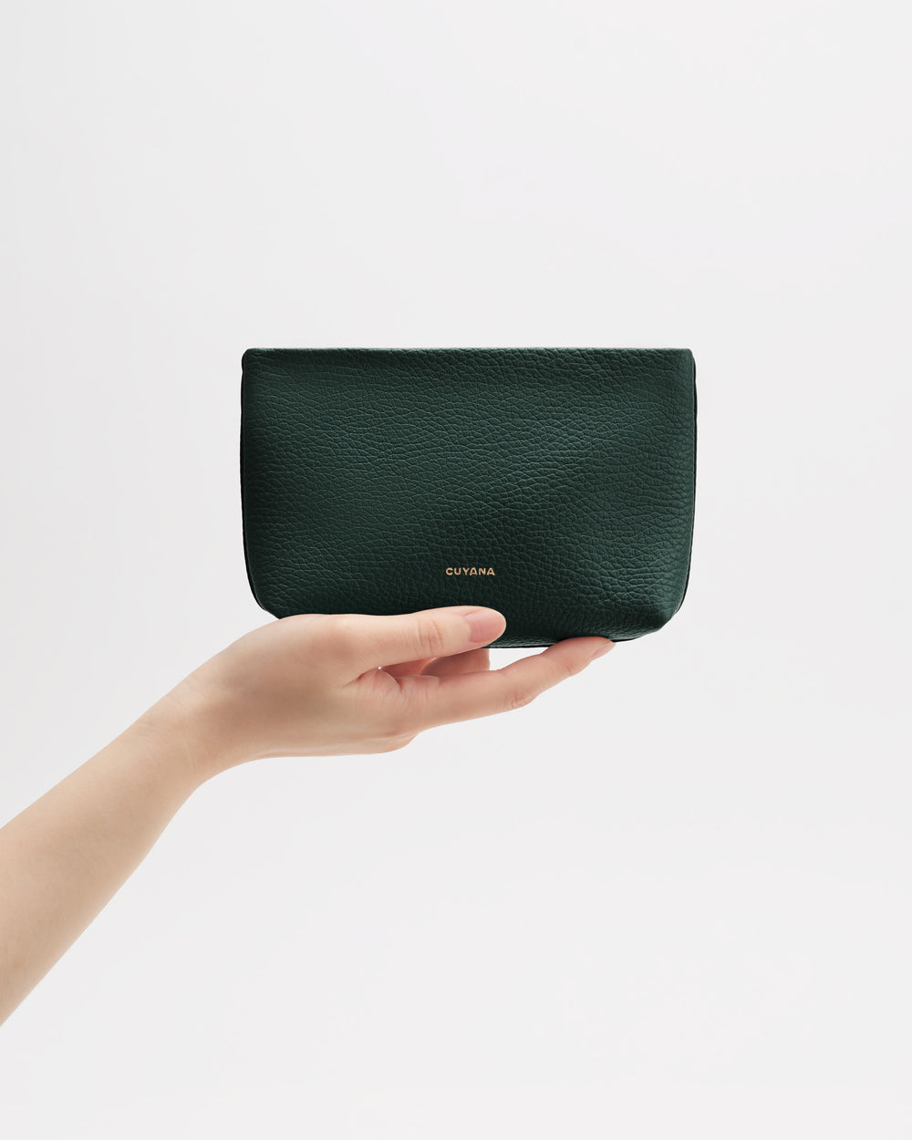 Hand holding a small pouch against a plain background