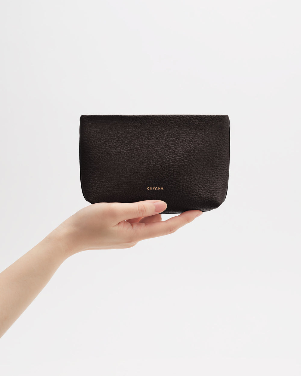 Hand holding a small pouch against a plain background.