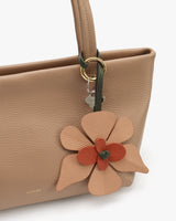 Handbag with a large flower-shaped accessory attached to the handle.