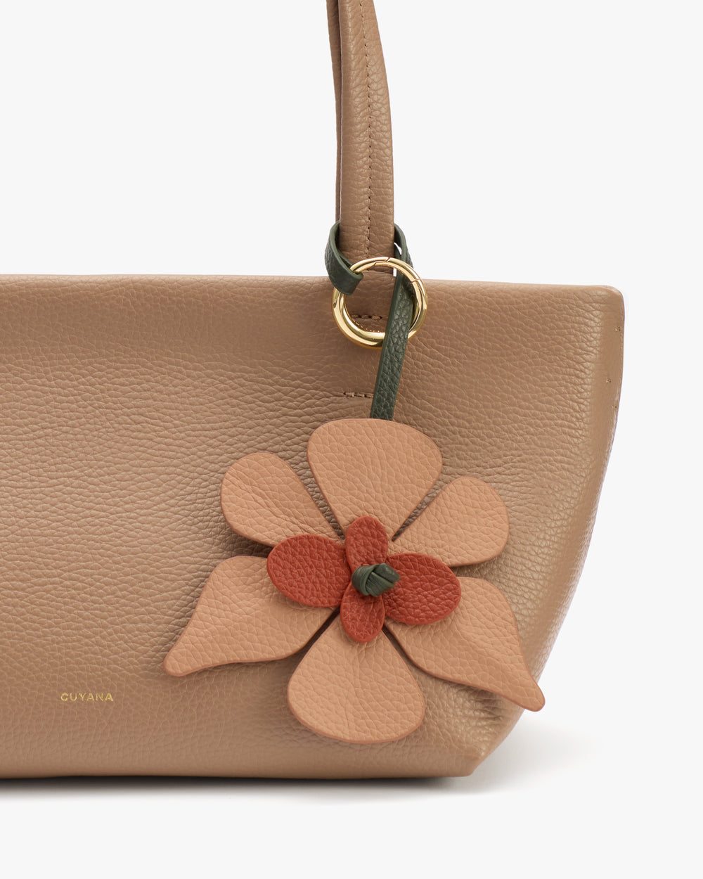 Handbag with a floral ornament attached to the handle.