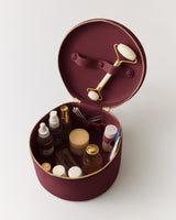 Round makeup case with skincare products and facial roller inside.
