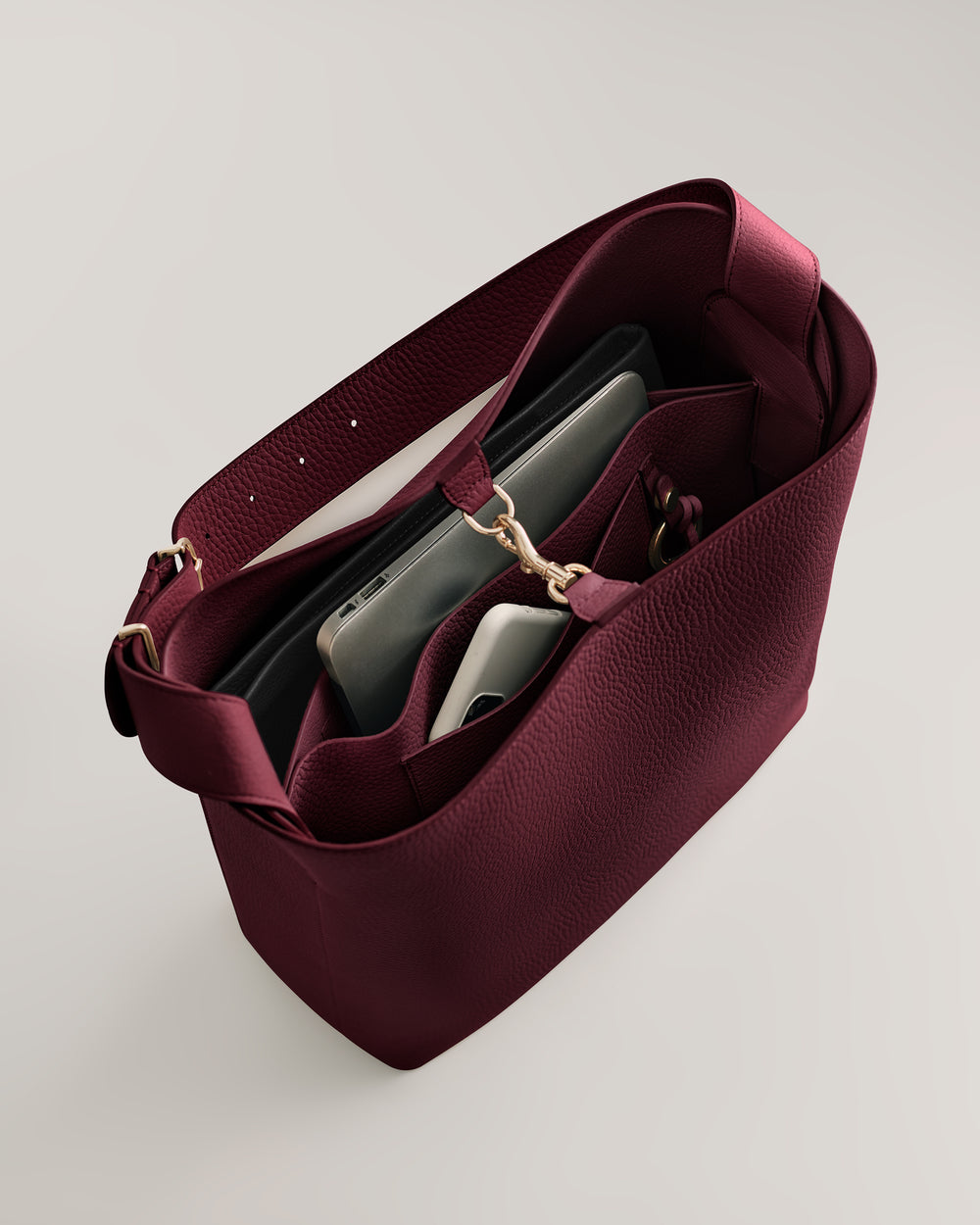 Open handbag with compartments and two electronic devices inside.