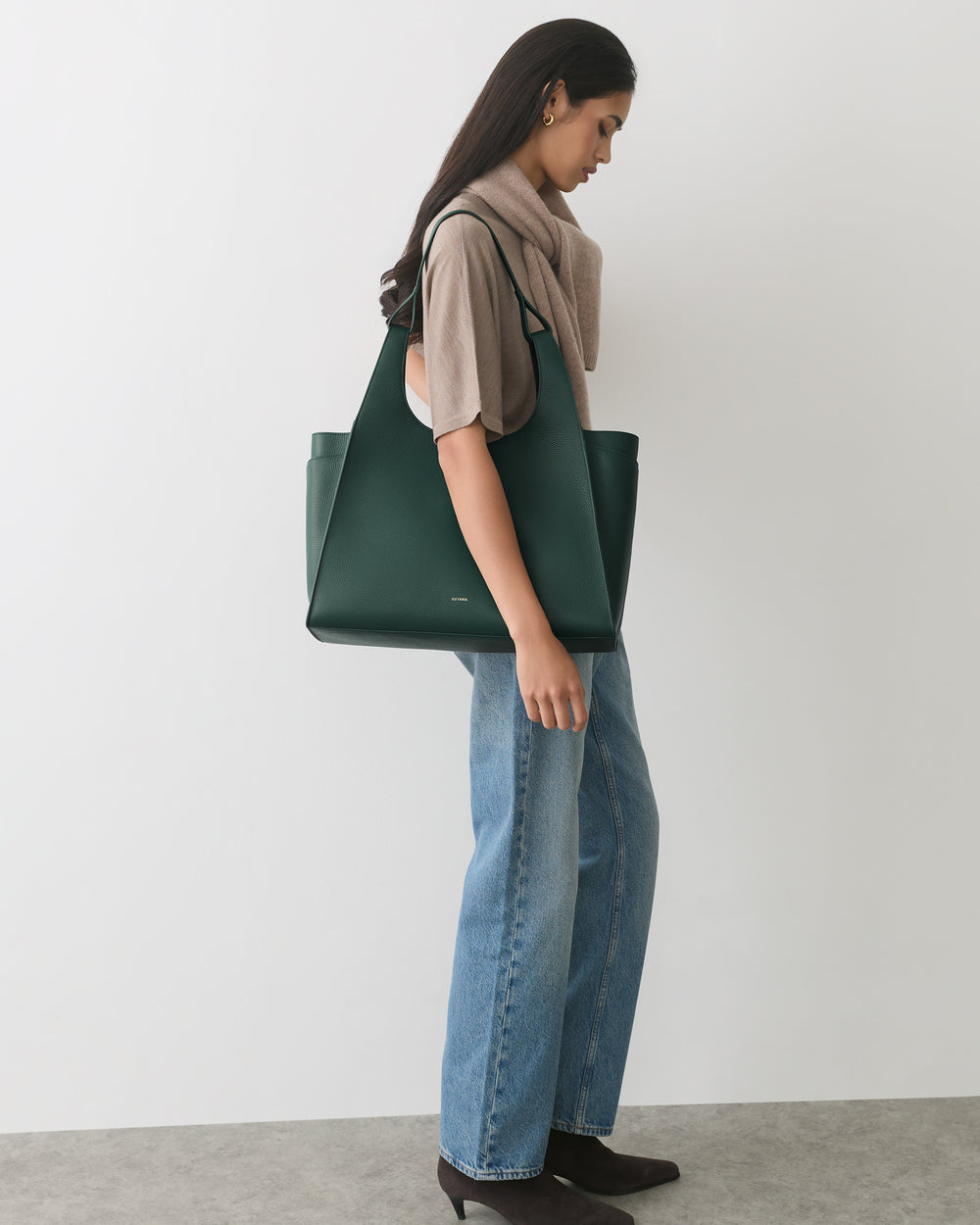 Person standing with large handbag, wearing jeans and boots