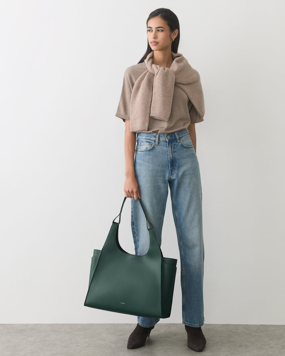 Person in casual outfit holding a large handbag.