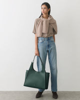 Person in casual outfit holding a large handbag.