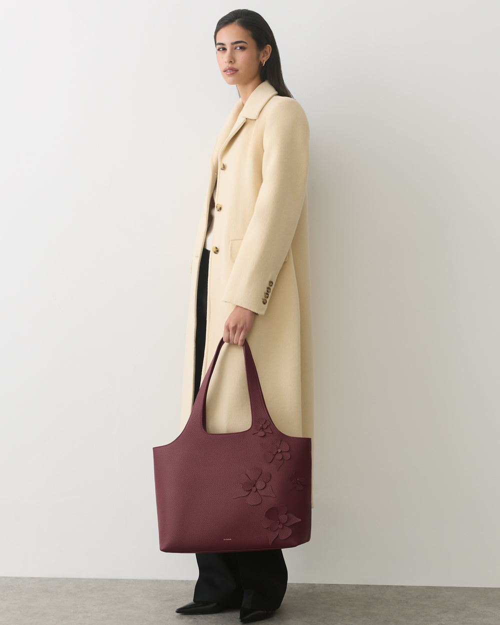 Person wearing long coat holding a large bag with floral patterns