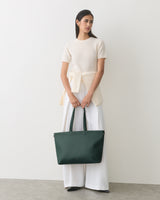 Model holding a large travel bag wearing a short-sleeve top and wide-leg pants.