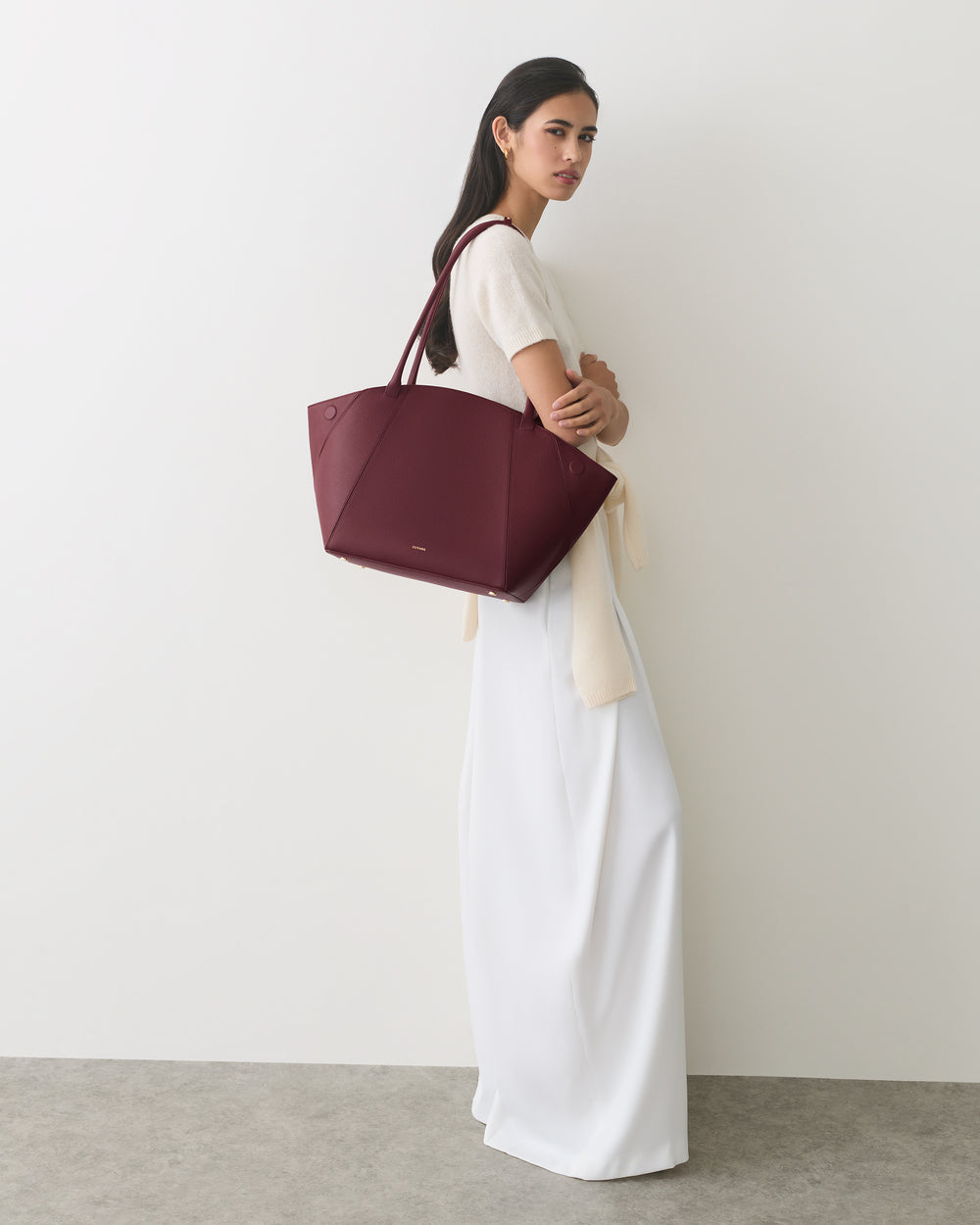 Person in long dress holding a large handbag on their shoulder
