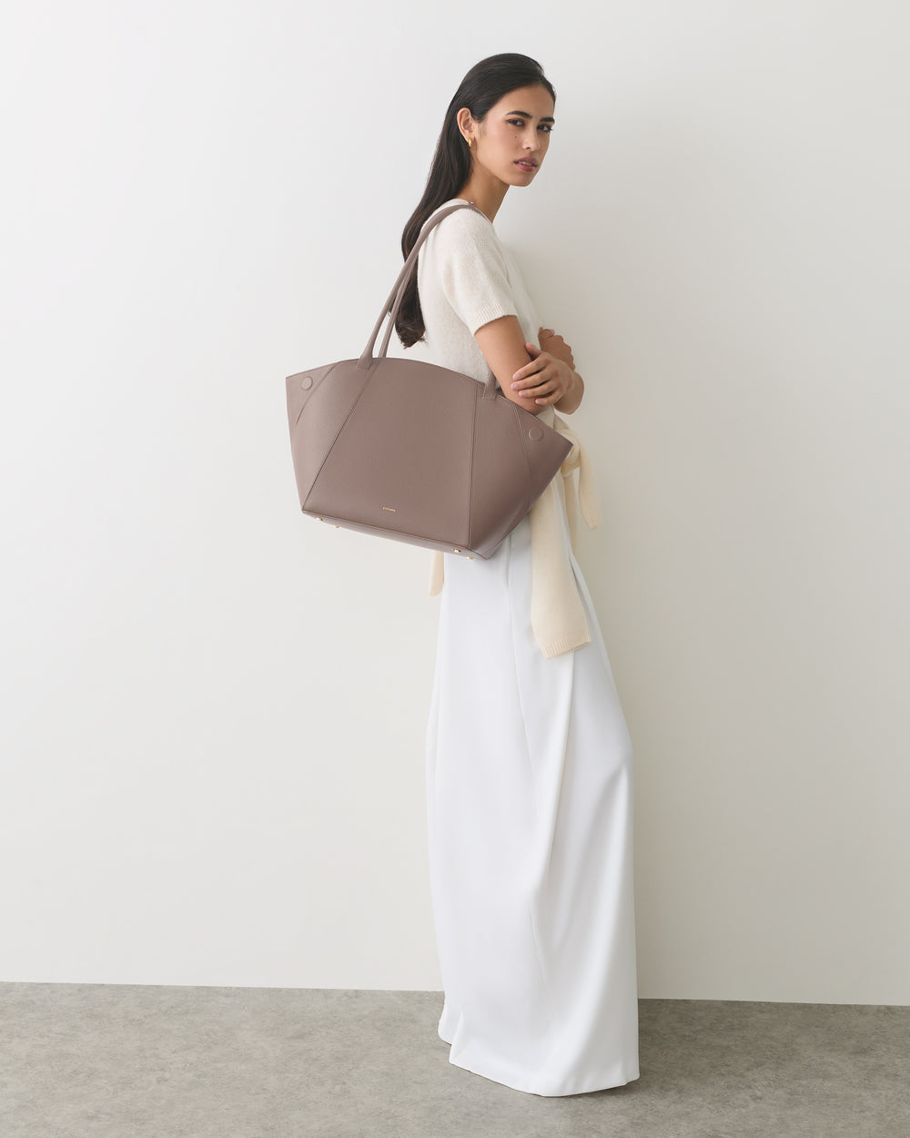 Person posing with large tote bag on shoulder.