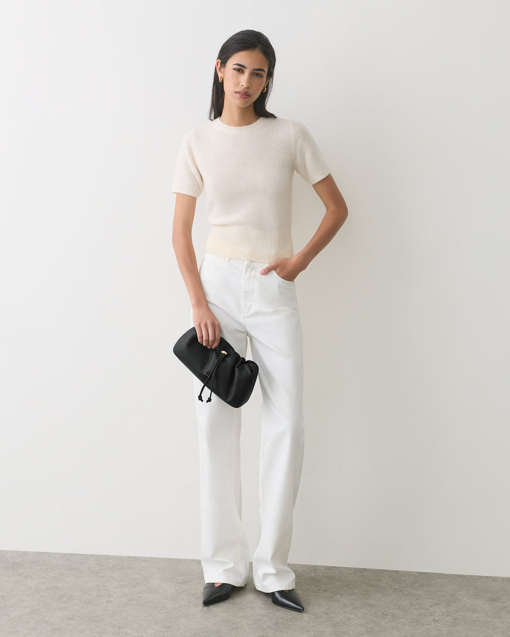 Person wearing a short-sleeve shirt and pants, holding a small bag.