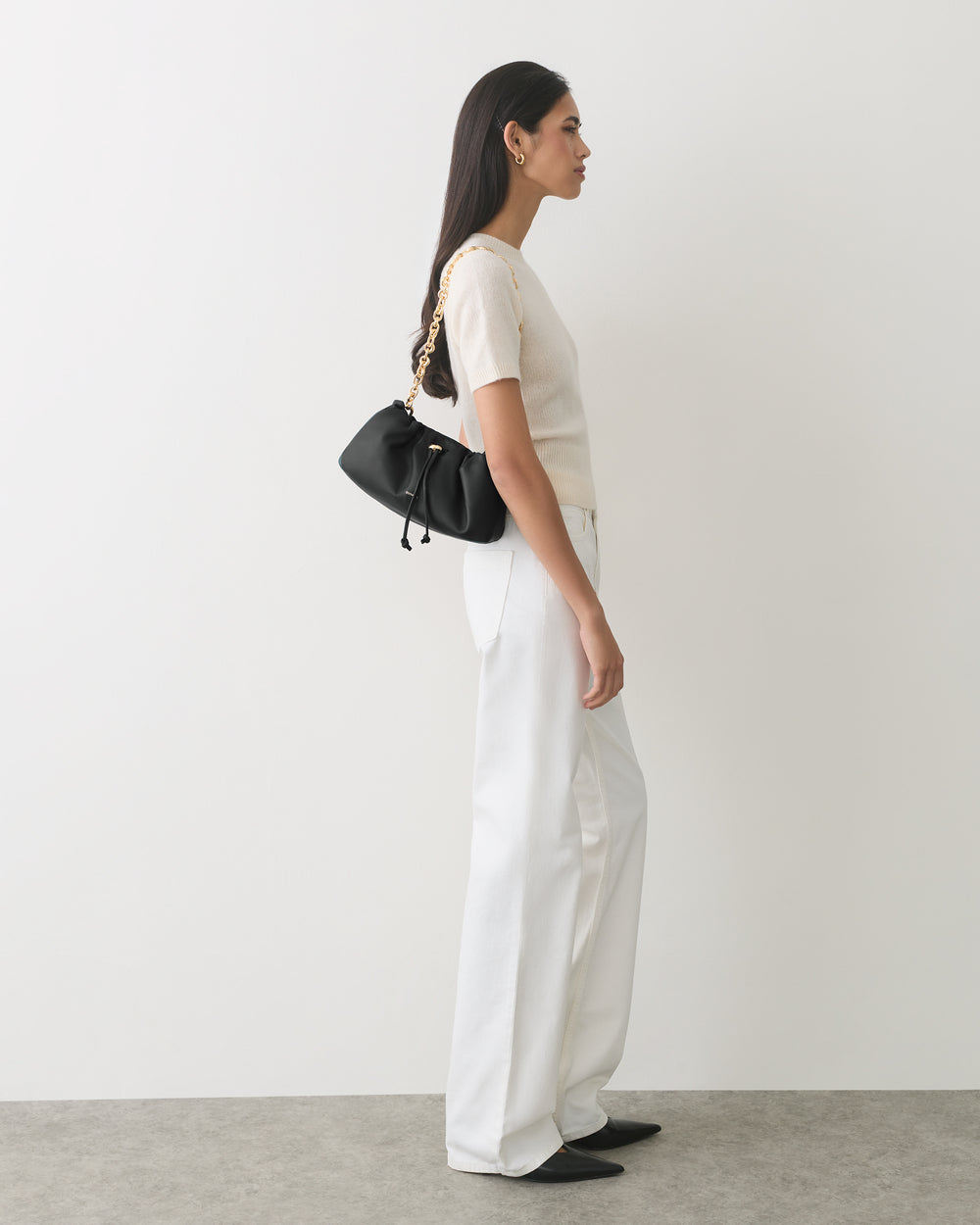 Person in a short-sleeve top and pants carrying a shoulder bag.