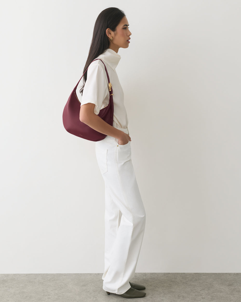 Person in profile wearing casual outfit with shoulder bag.