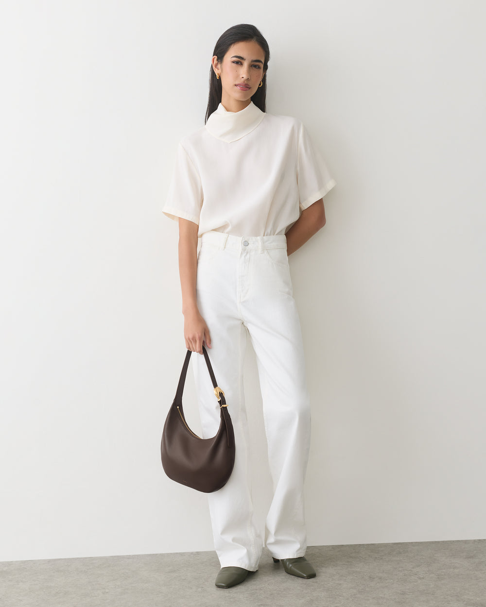 Person in a shirt and pants holding a shoulder bag.