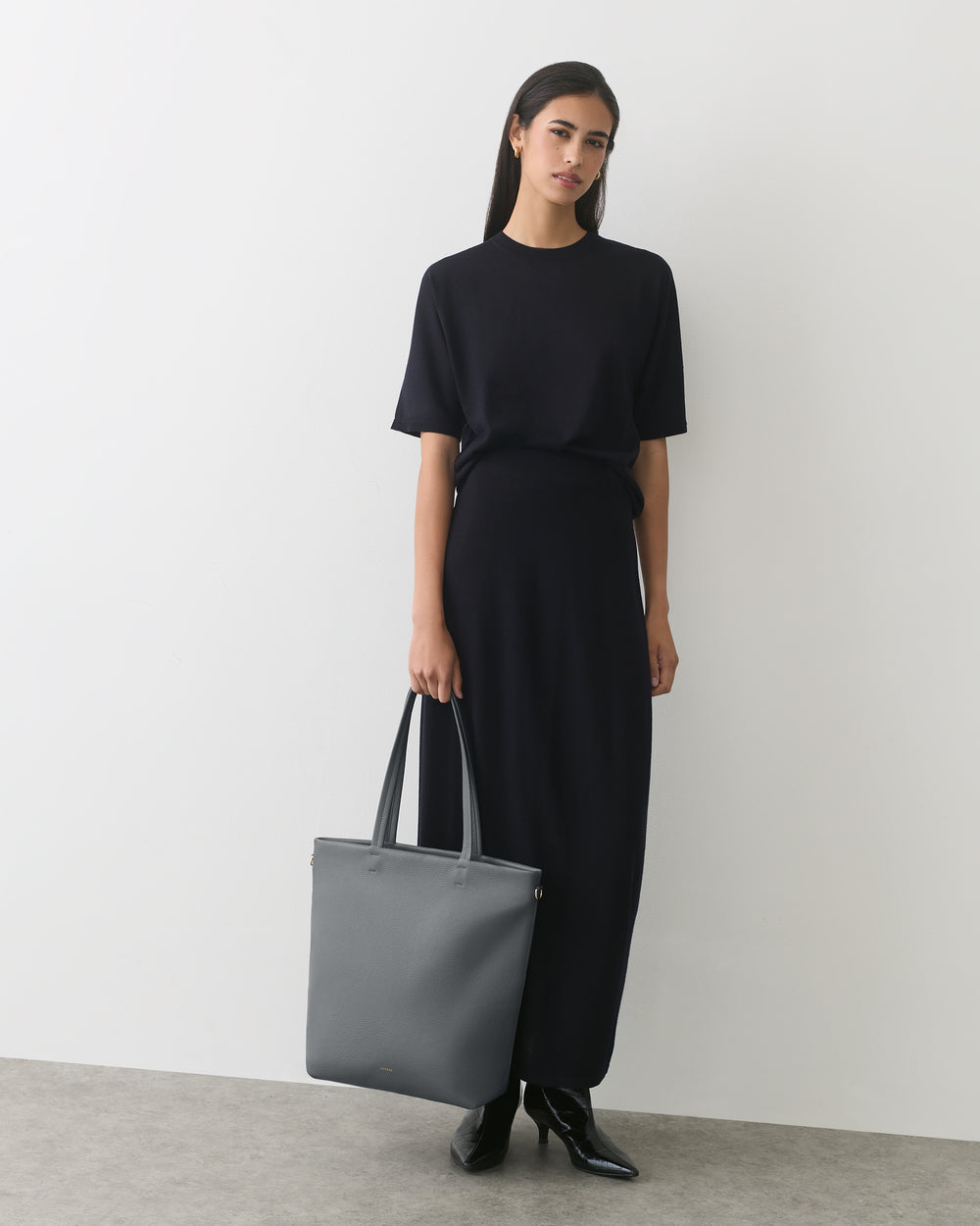 Person in long dress holding a large tote bag
