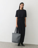 Person in long dress holding a large tote bag
