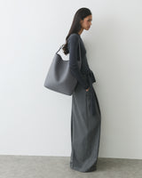 Person in trousers and a sweater, wearing a large shoulder bag.