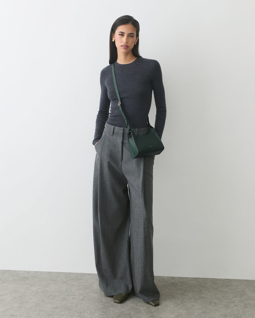 Person wearing long-sleeve top, wide-leg pants, and shoulder bag.