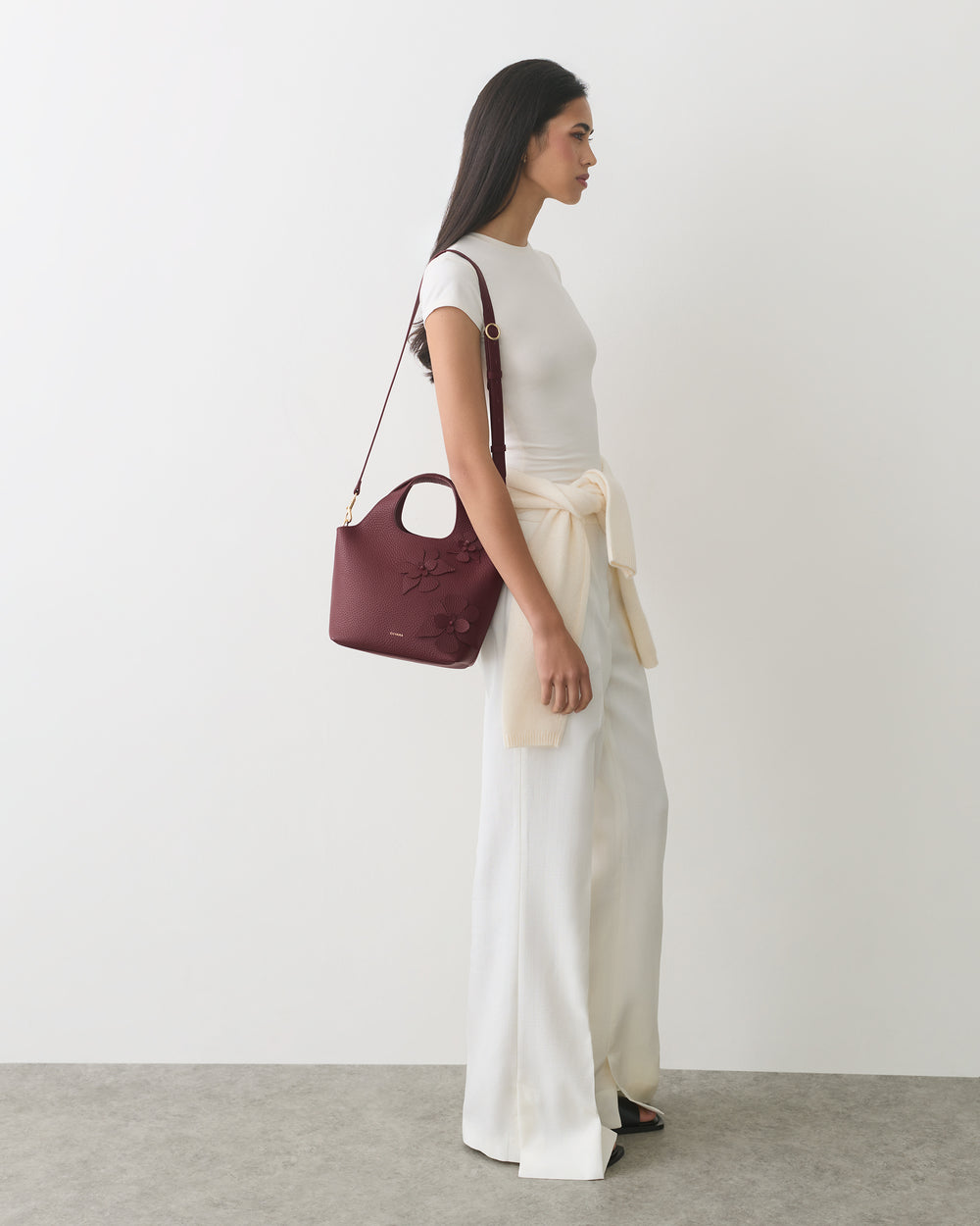 Person in long pants and top, carrying shoulder bag with floral detail
