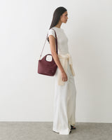 Person in long pants and top, carrying shoulder bag with floral detail
