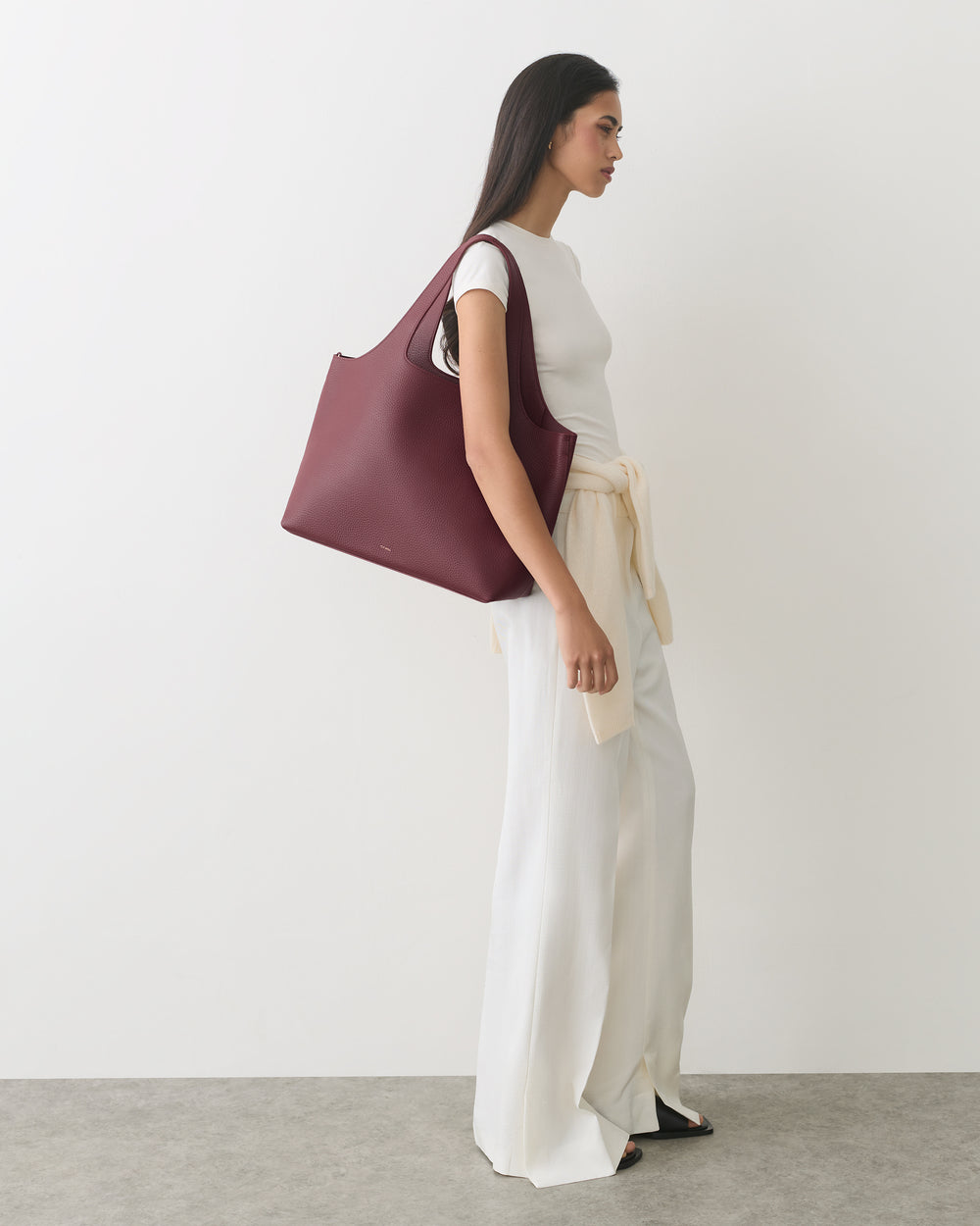 Person in a sleeveless top and wide pants carrying a large handbag.