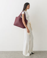 Person in a sleeveless top and wide pants carrying a large handbag.