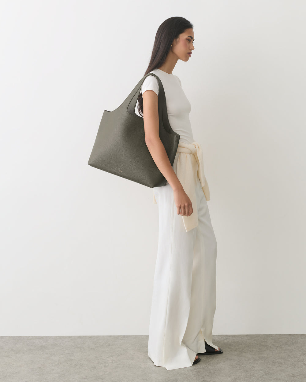 A person carrying a large bag wearing a top and loose pants.