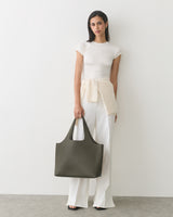 Person posing with a large handbag and wearing casual attire.