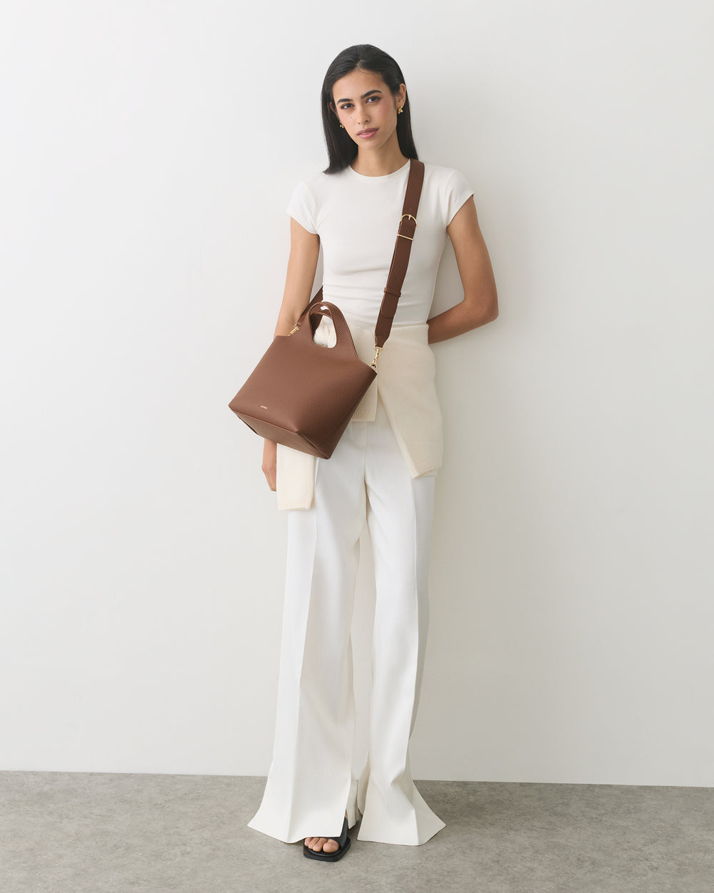 Person standing with a handbag, wearing a t-shirt and pants.