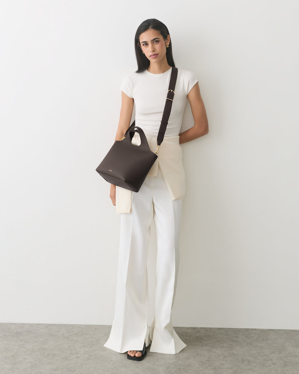 Person with over-the-shoulder bag wearing a short-sleeve top and wide-leg pants.