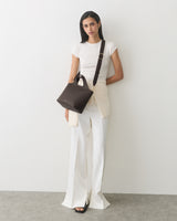 Person with over-the-shoulder bag wearing a short-sleeve top and wide-leg pants.