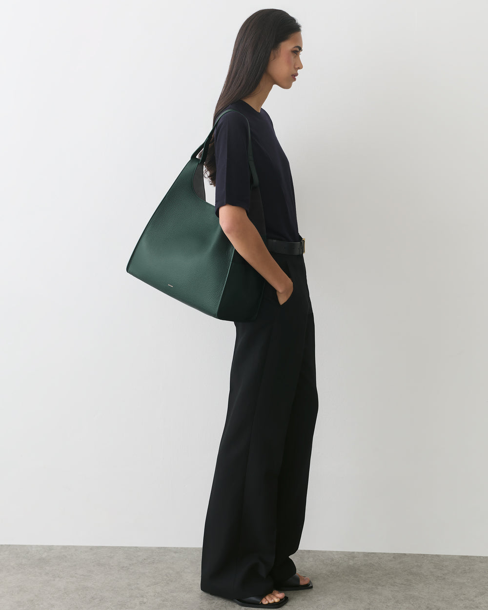 Person in profile with a wide-leg outfit carrying a shoulder bag