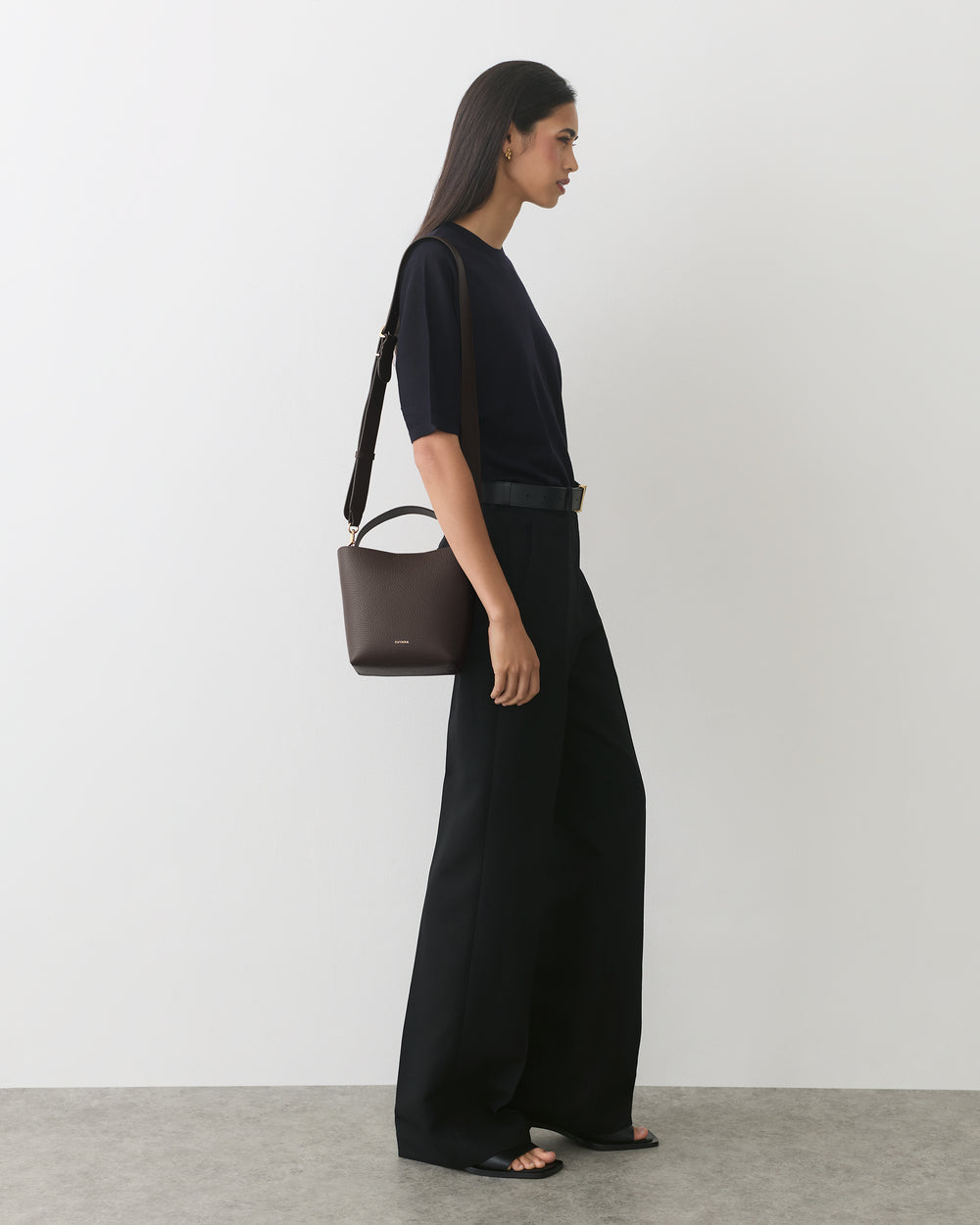 Person in a shirt and wide-leg pants carrying a handbag over the shoulder