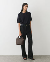 Woman in a t-shirt and pants holding a small handbag.