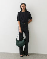 Person wearing a shirt and pants, holding a bag in one hand.