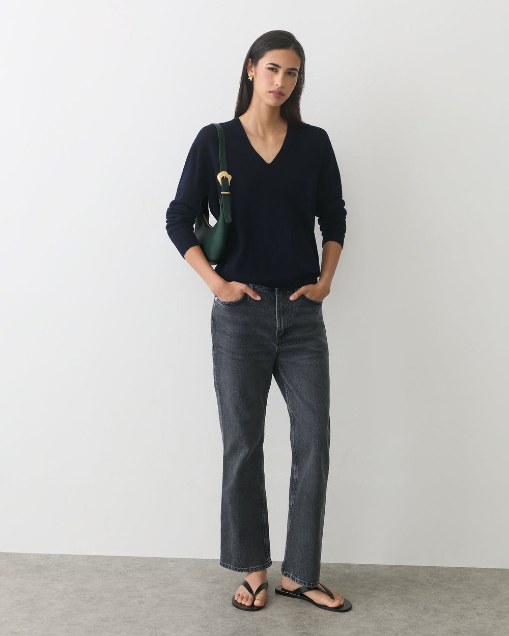 Person wearing a sweater, jeans, sandals, and carrying a bag over shoulder.