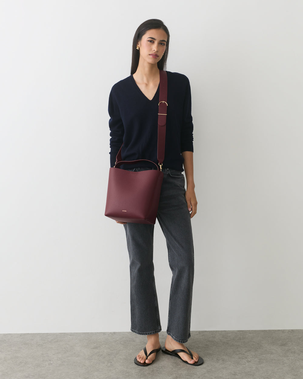 Person standing with bucket bag wearing casual outfit and sandals