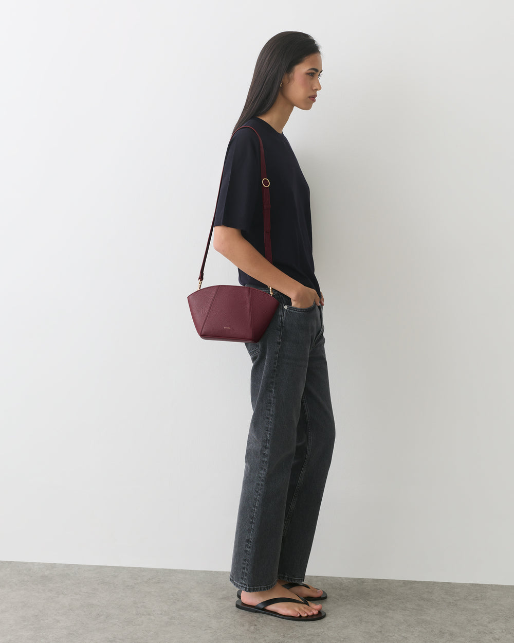 Person in casual outfit with a shoulder bag standing sideways.