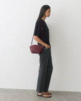 Person in casual outfit with a shoulder bag standing sideways.