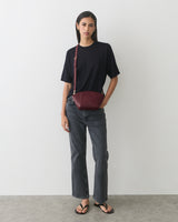 Person in t-shirt and jeans with a belt bag over shoulder.