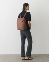 Person wearing a backpack, standing with hands in pockets.