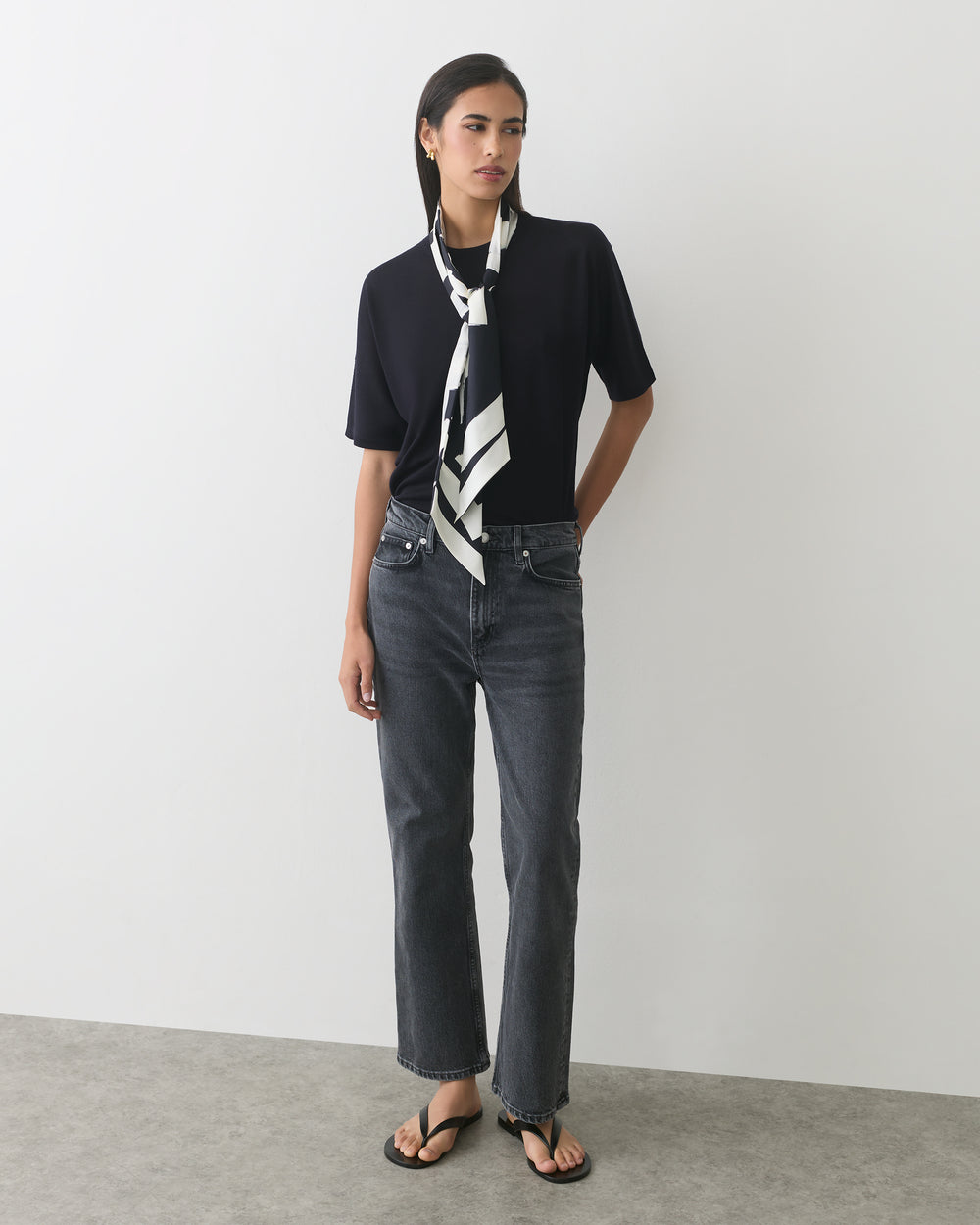 Person wearing a shirt, jeans, sandals, and a patterned scarf.