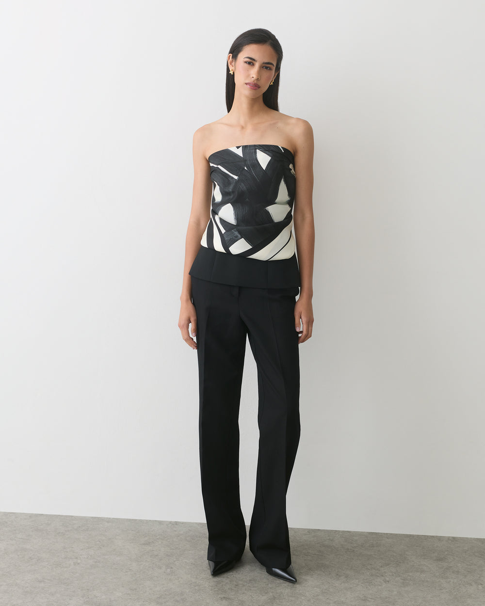 A person wearing a patterned strapless top and pants, standing on a plain background.